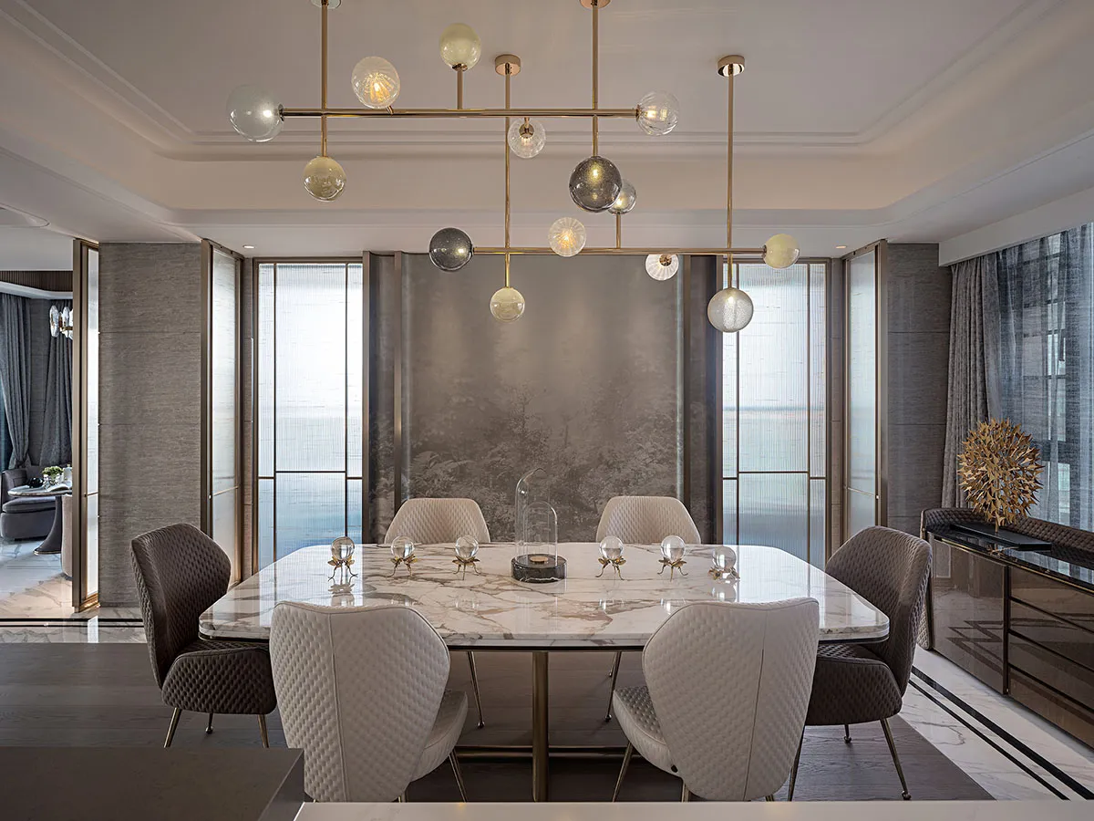 A contemporary dining room featuring a marble table with geometric patterns, surrounded by modern chairs, and illuminated by