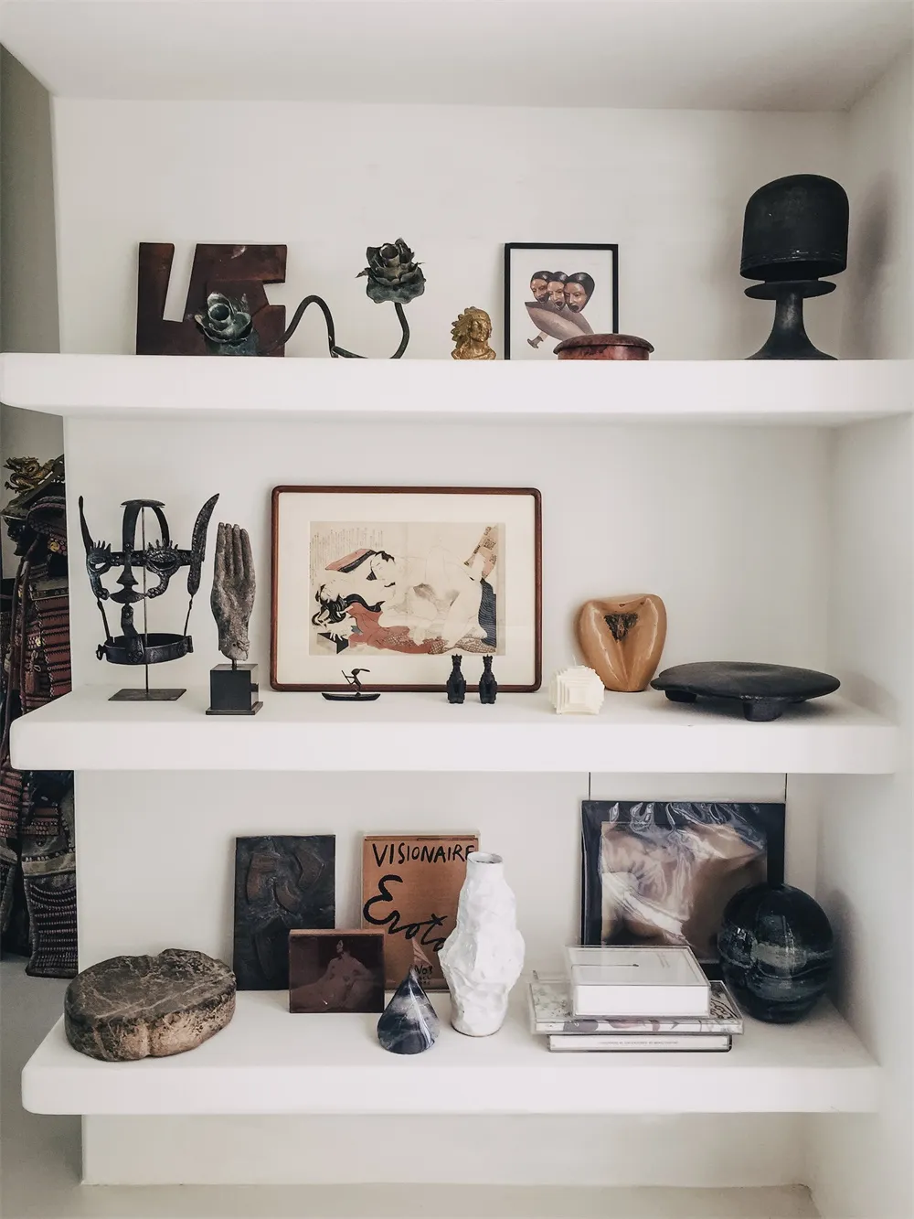 精心策展的展示櫃，陳列各種雕塑、藝術品與物件，排列於三層層板上，展現潛水