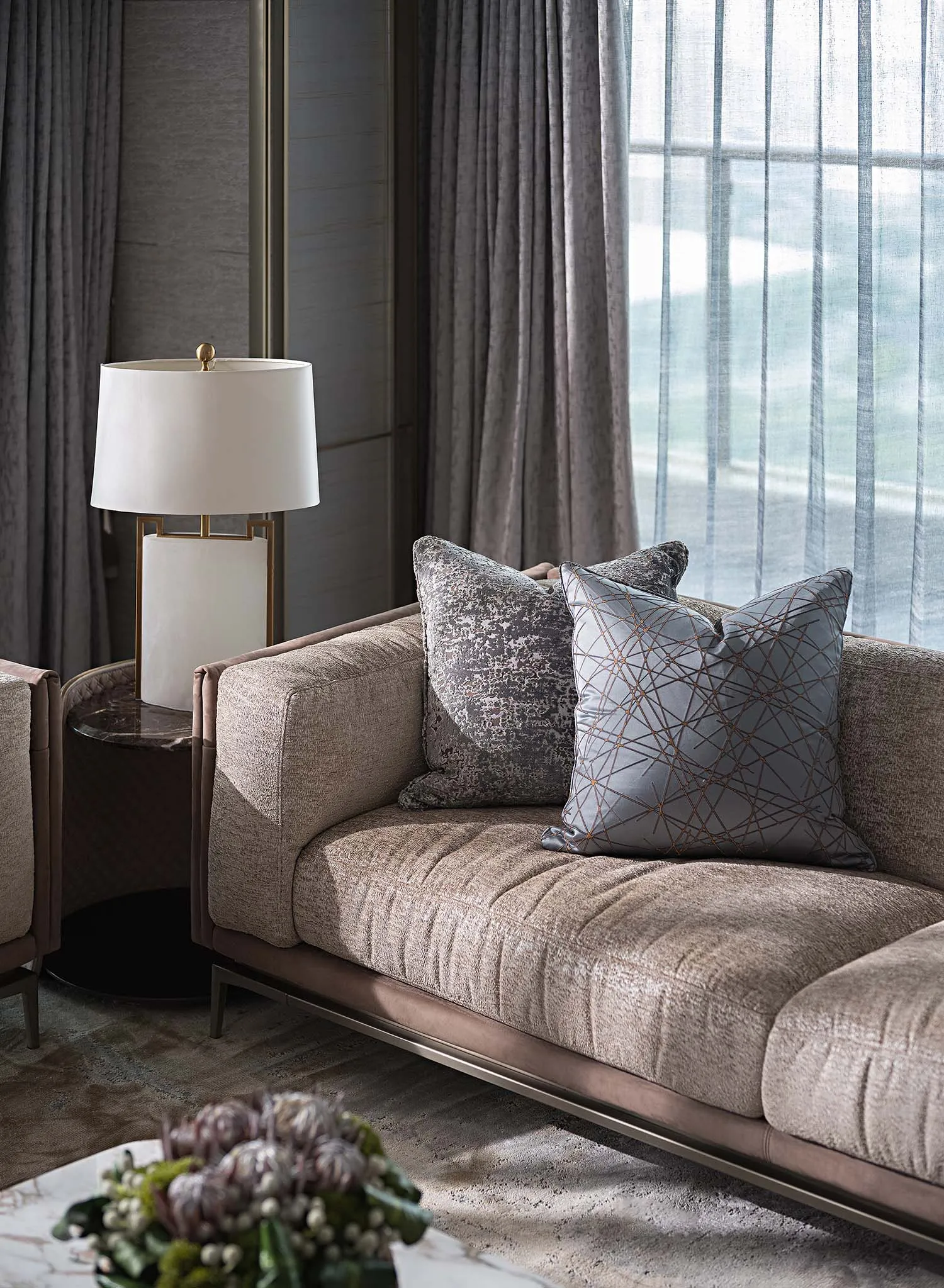 A modern living room featuring a plush, taupe-colored sofa adorned with geometric-patterned throw pillows, accompanied by a f