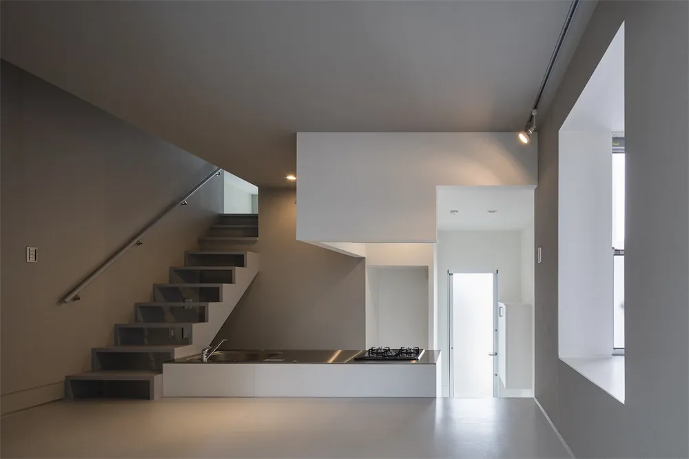 Modern minimalist kitchen with white countertops and minimalist furniture.