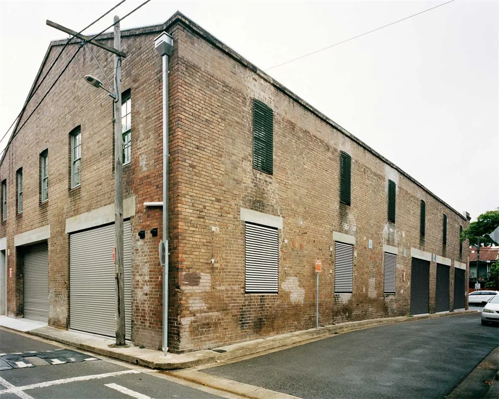 A street view of a brick building with roller shutters and a street light.