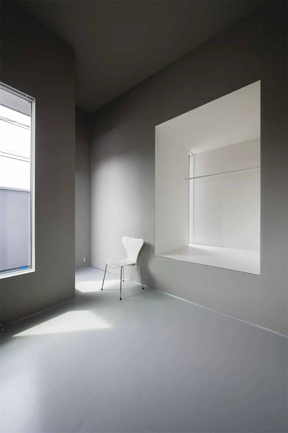 A minimalist white interior space with layered lighting and grey walls.