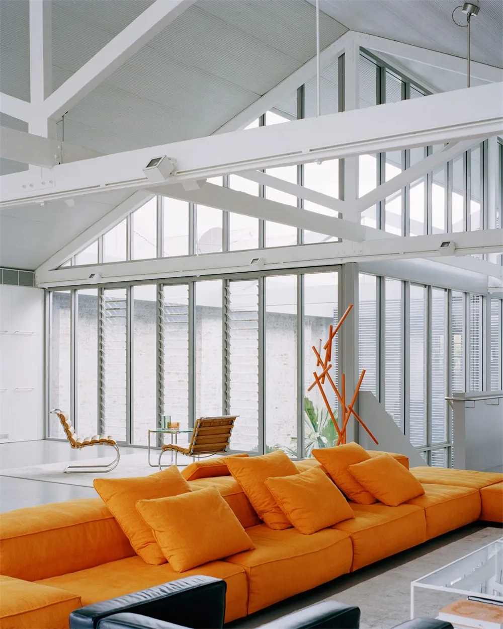 現代客廳擺放鮮豔橘色L型沙發、黑白單椅與俐落家具。
