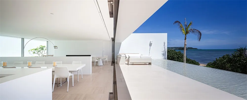 Modern living room interior with white marble floor and walls, featuring contemporary furniture and large windows overlooking