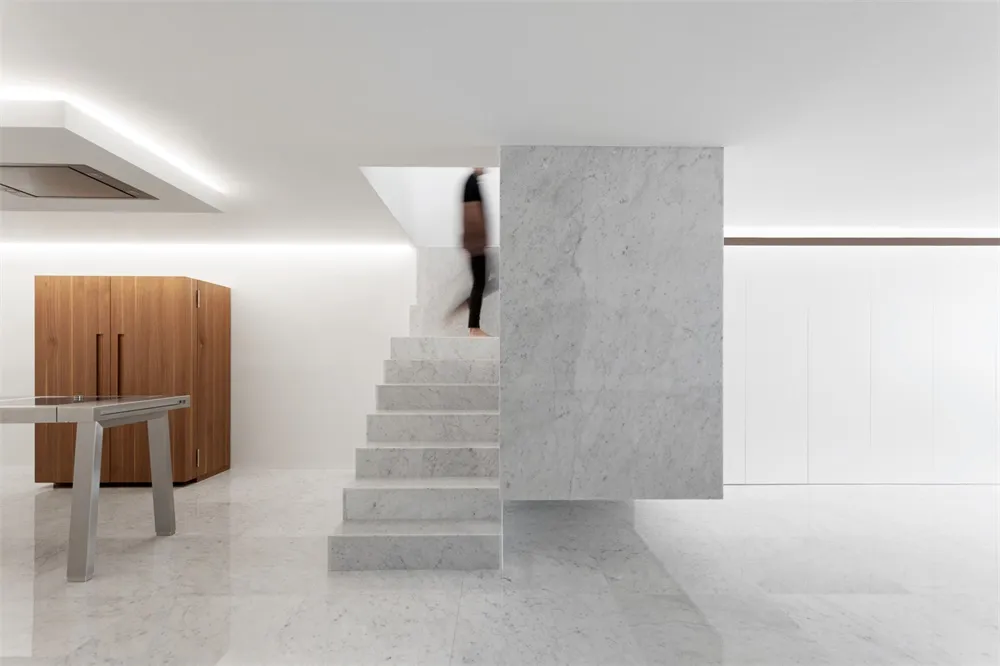 A modern interior space featuring a marble staircase and a wooden cabinet.