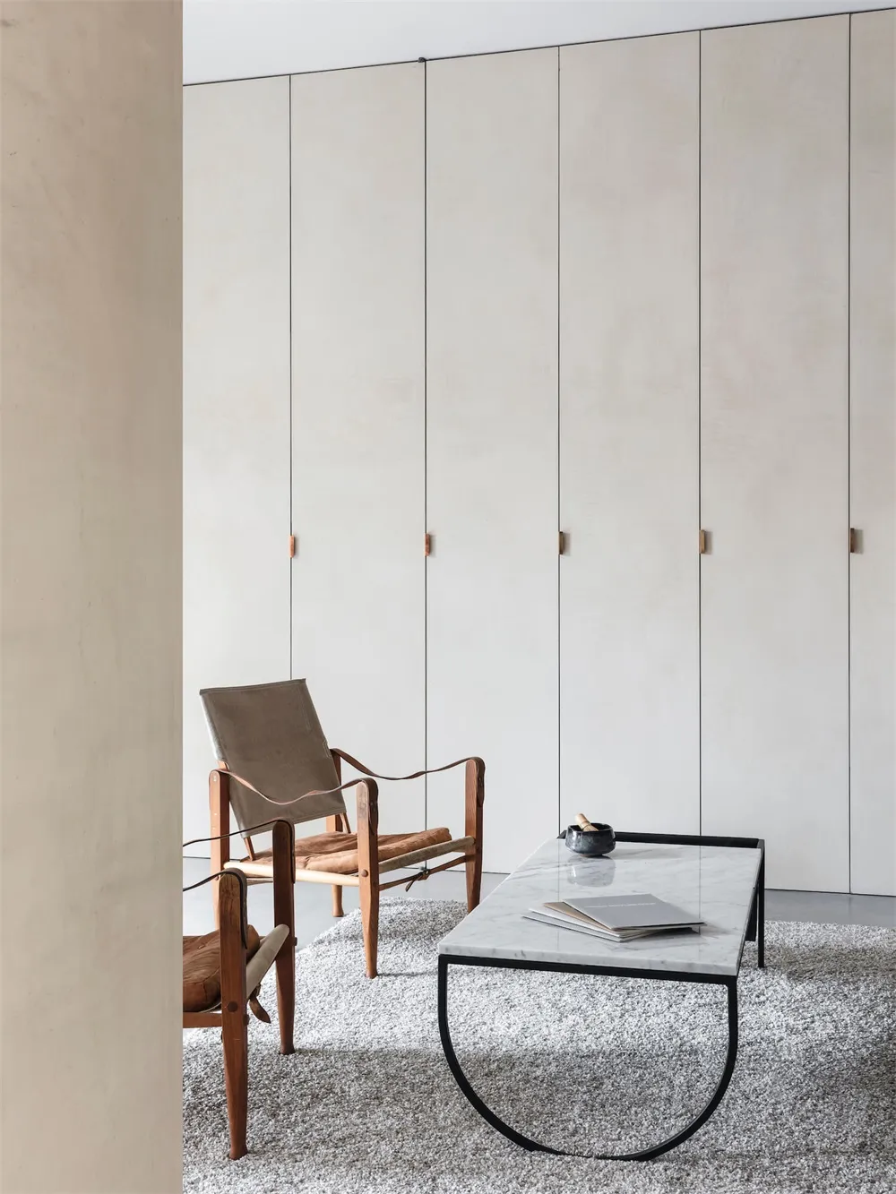 Modern minimalist living room featuring wood, leather, and marble accents.