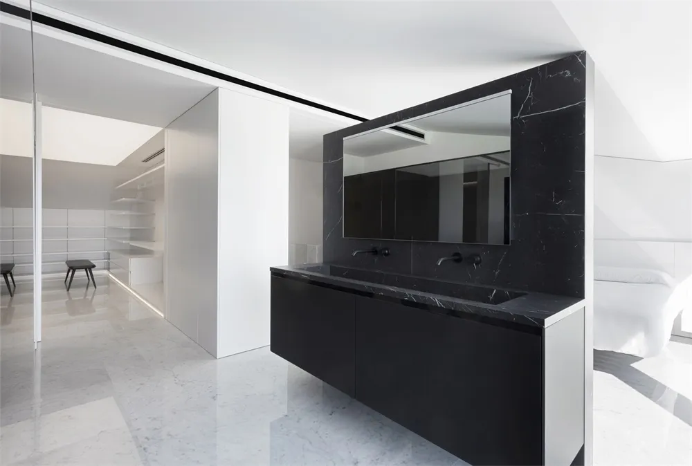 Modern, minimalist bathroom featuring black marble sink and white marble flooring.