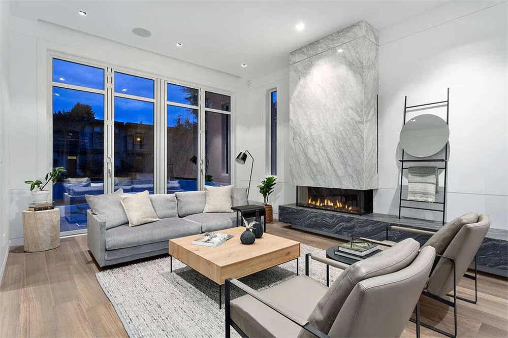 A modern living room with a marble fireplace and wooden furniture.
