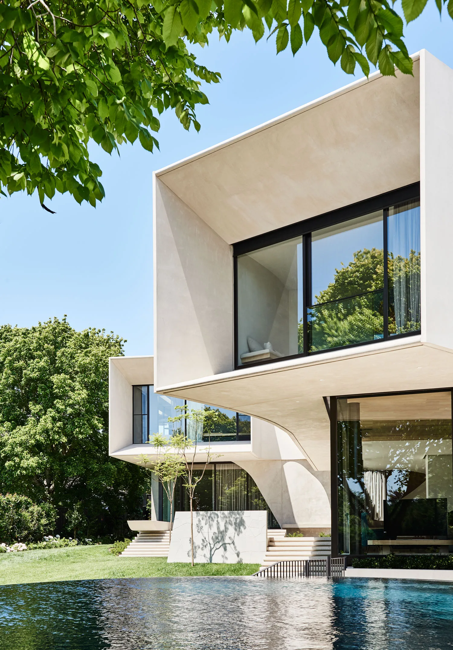 Modern house with concrete exterior featuring large glass windows and a swimming pool.