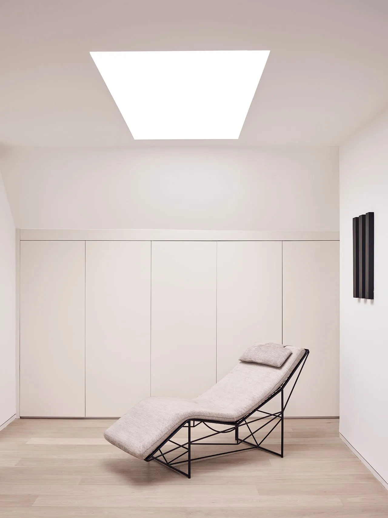 A minimalist chaise lounger with white upholstery and a contemporary design.