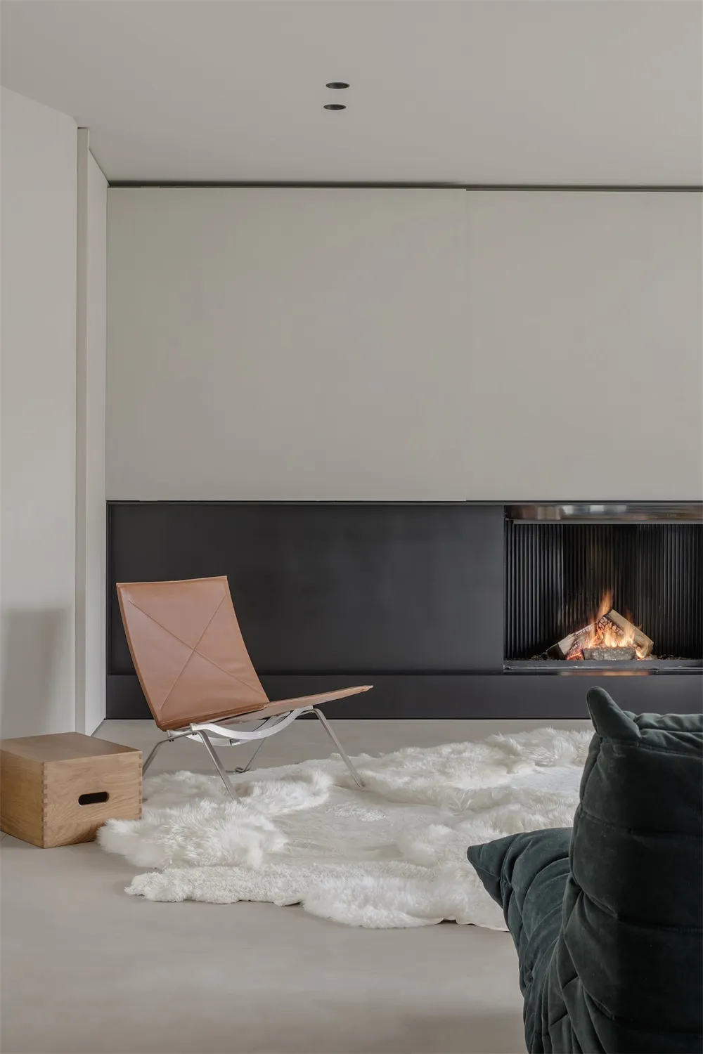 Minimalist living room with a leather chair and a fireplace, featuring a modern design aesthetic.