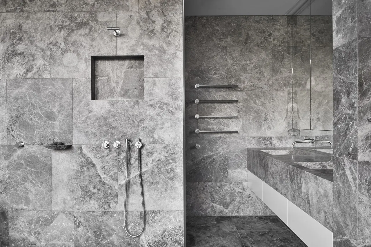 A modern bathroom with marble walls and a sink.
