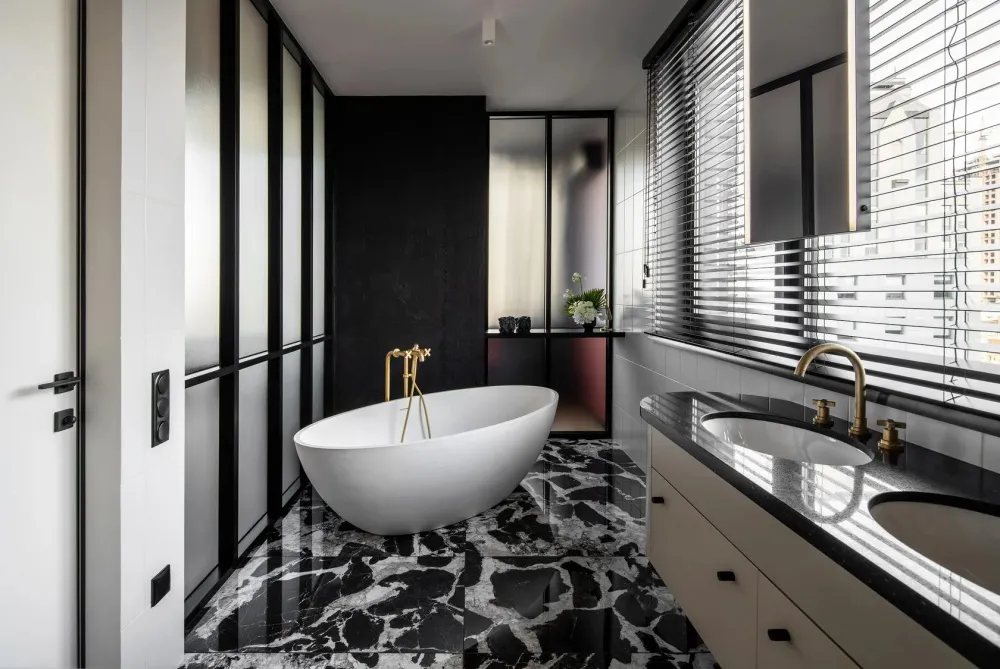 Modern bathroom with a freestanding bathtub and double sinks on a black marble floor.