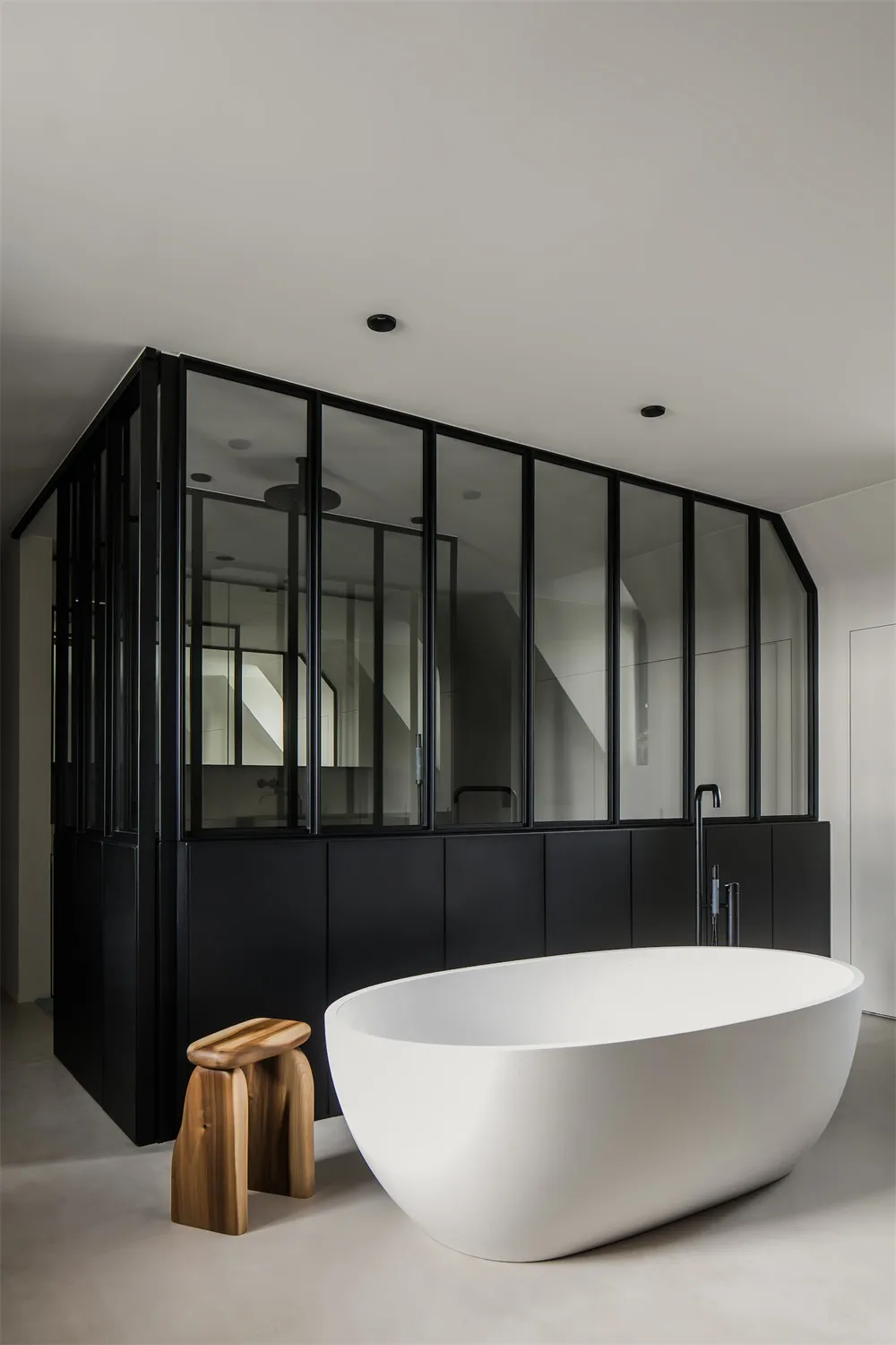 A minimalist bathroom with a smooth concrete floor and a white oval bathtub.