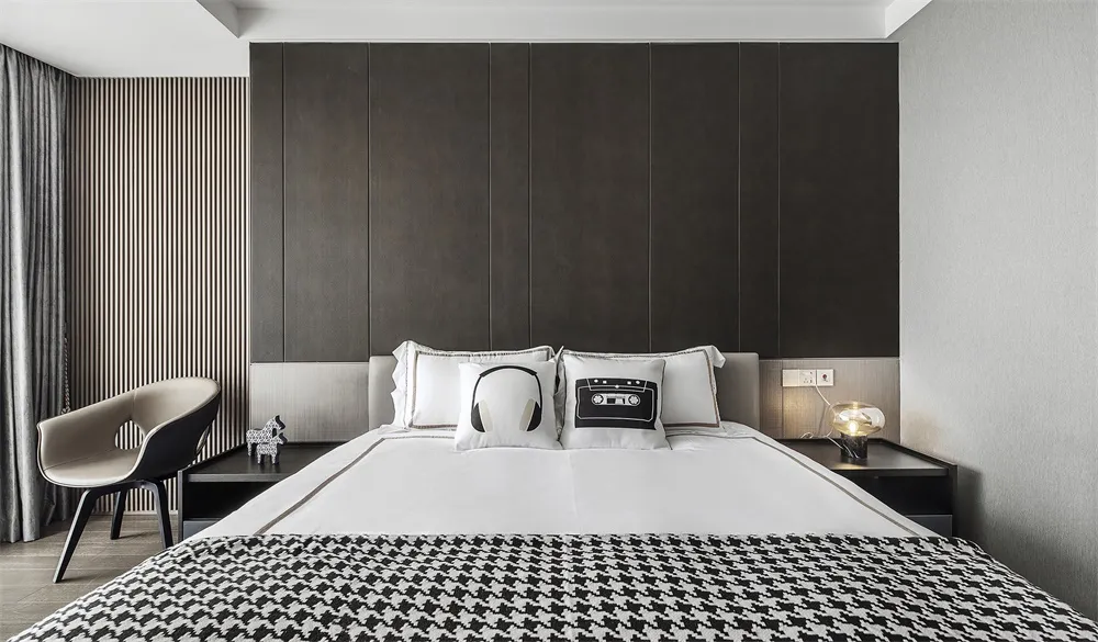 A modern bedroom with a black and white color scheme, featuring a bed with a black and white checkered blanket and decorative