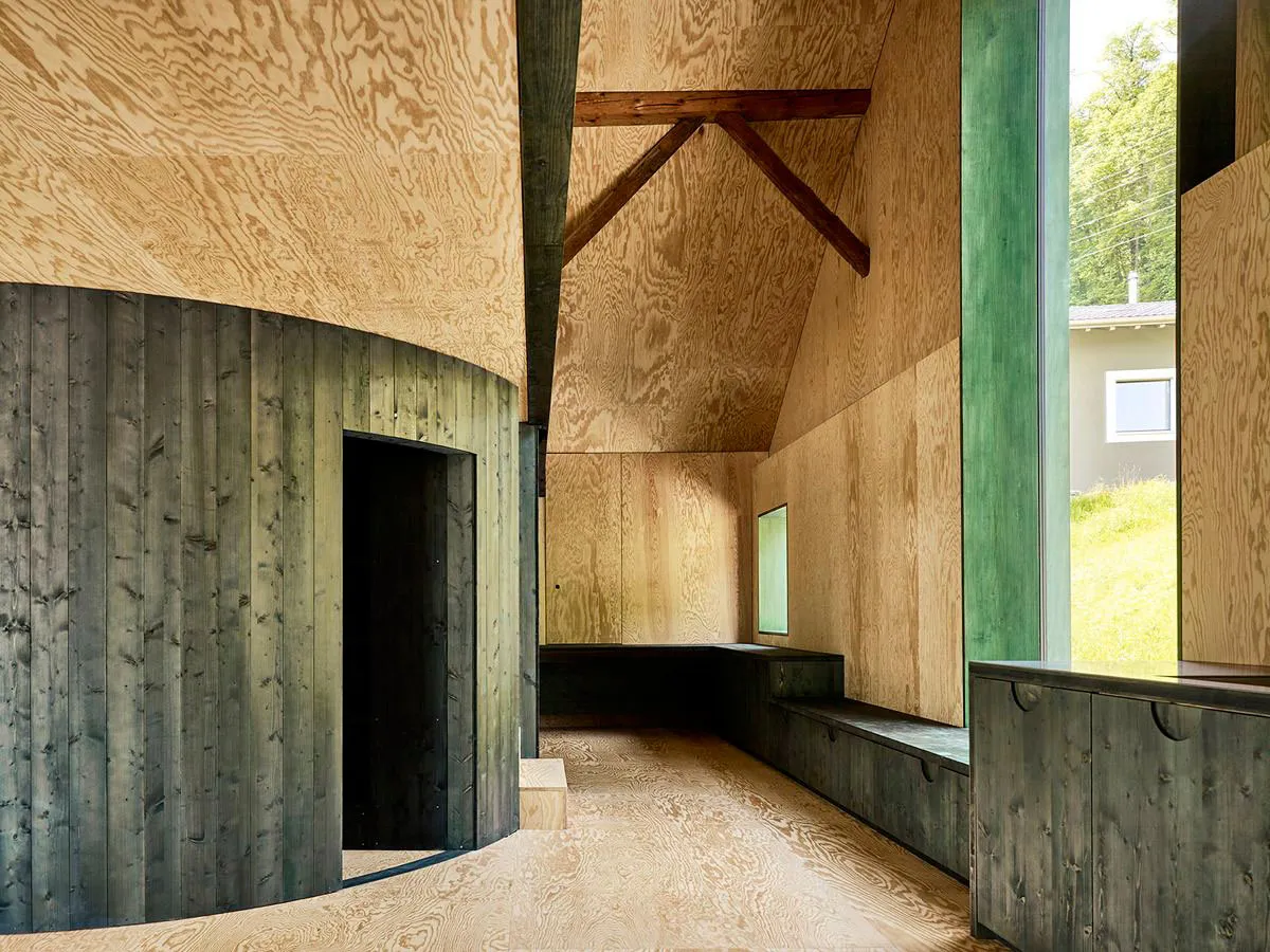 View of a modern interior featuring wood paneling, with a green window frame and a steeply pitched ceiling.