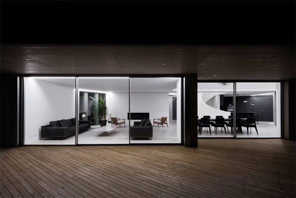 Modern living room with concrete walls and floor, featuring a cozy seating area and a minimalist design.
