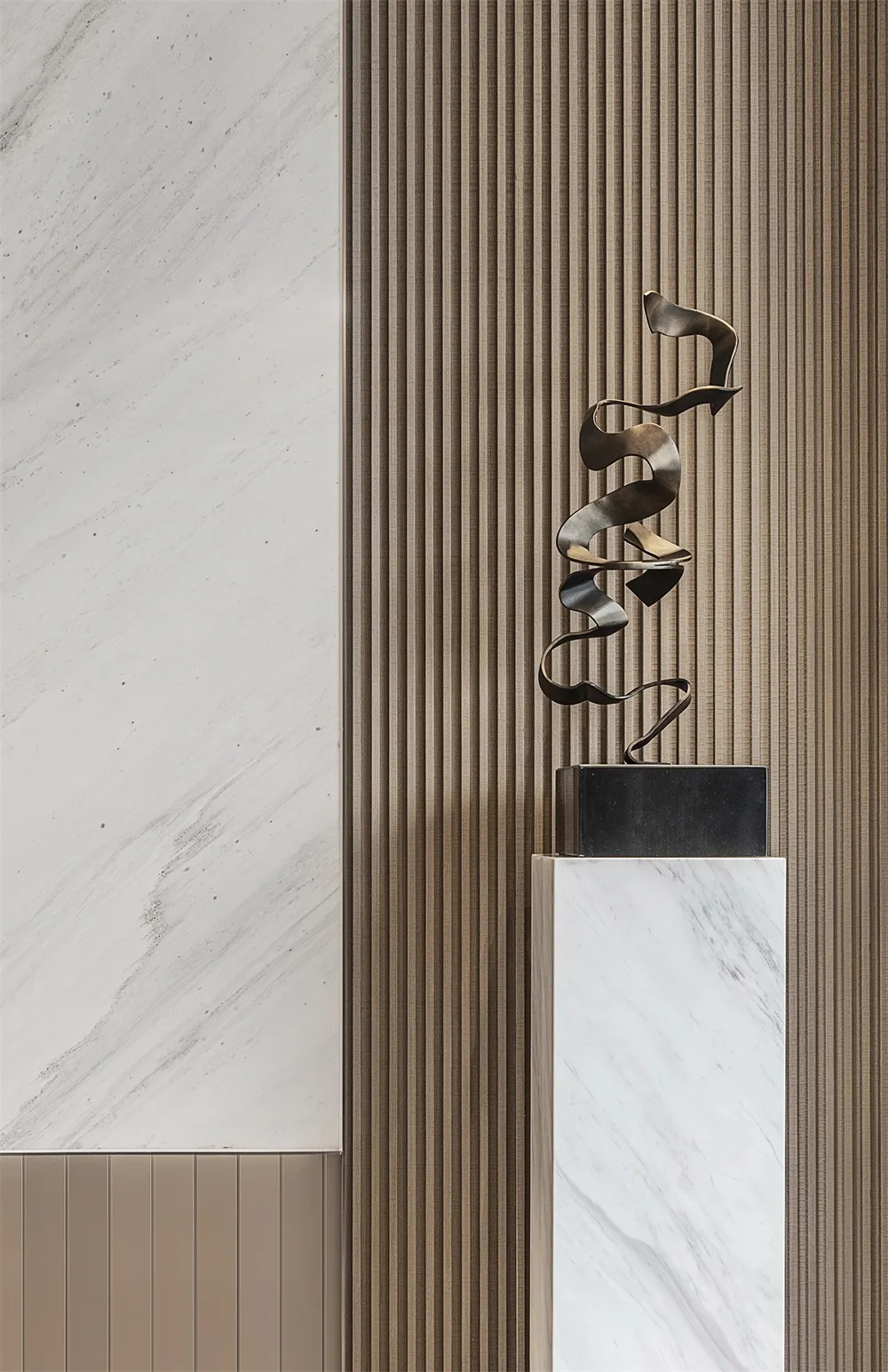 A modern metal sculpture displayed on a marble pedestal against a wooden panel background.