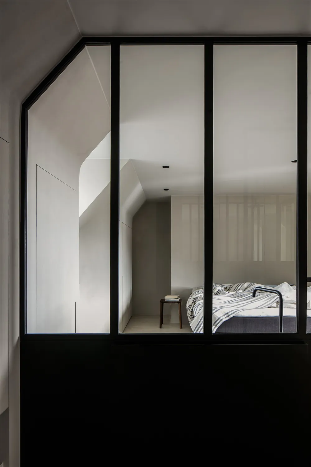A modern minimalist bedroom with concrete walls and a glass window.