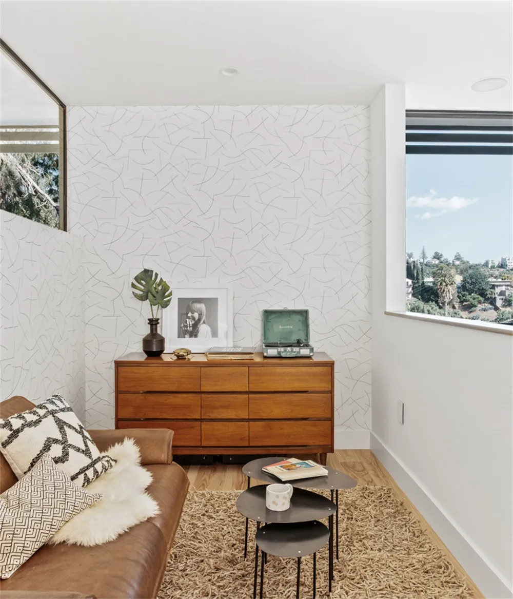 Modern minimalist living room featuring wooden furniture, a leather couch, and metal tables.