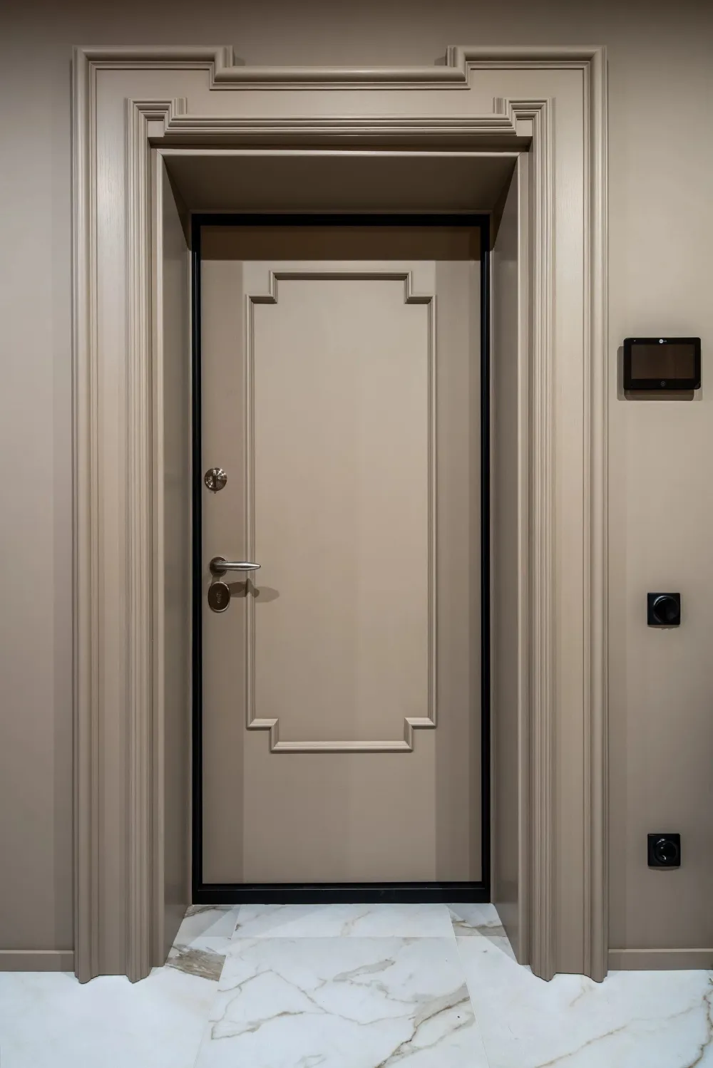 A modern minimalist doorway with a white marble floor and a metal-framed door.