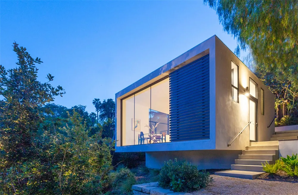 A modern residential exterior with concrete walls and a large window.