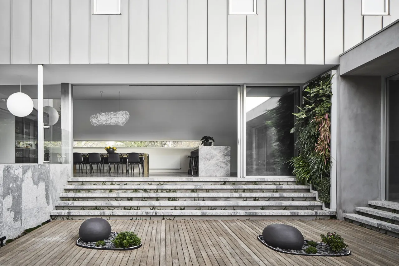 Modern residential interior featuring a concrete courtyard with steps and a wooden deck.
