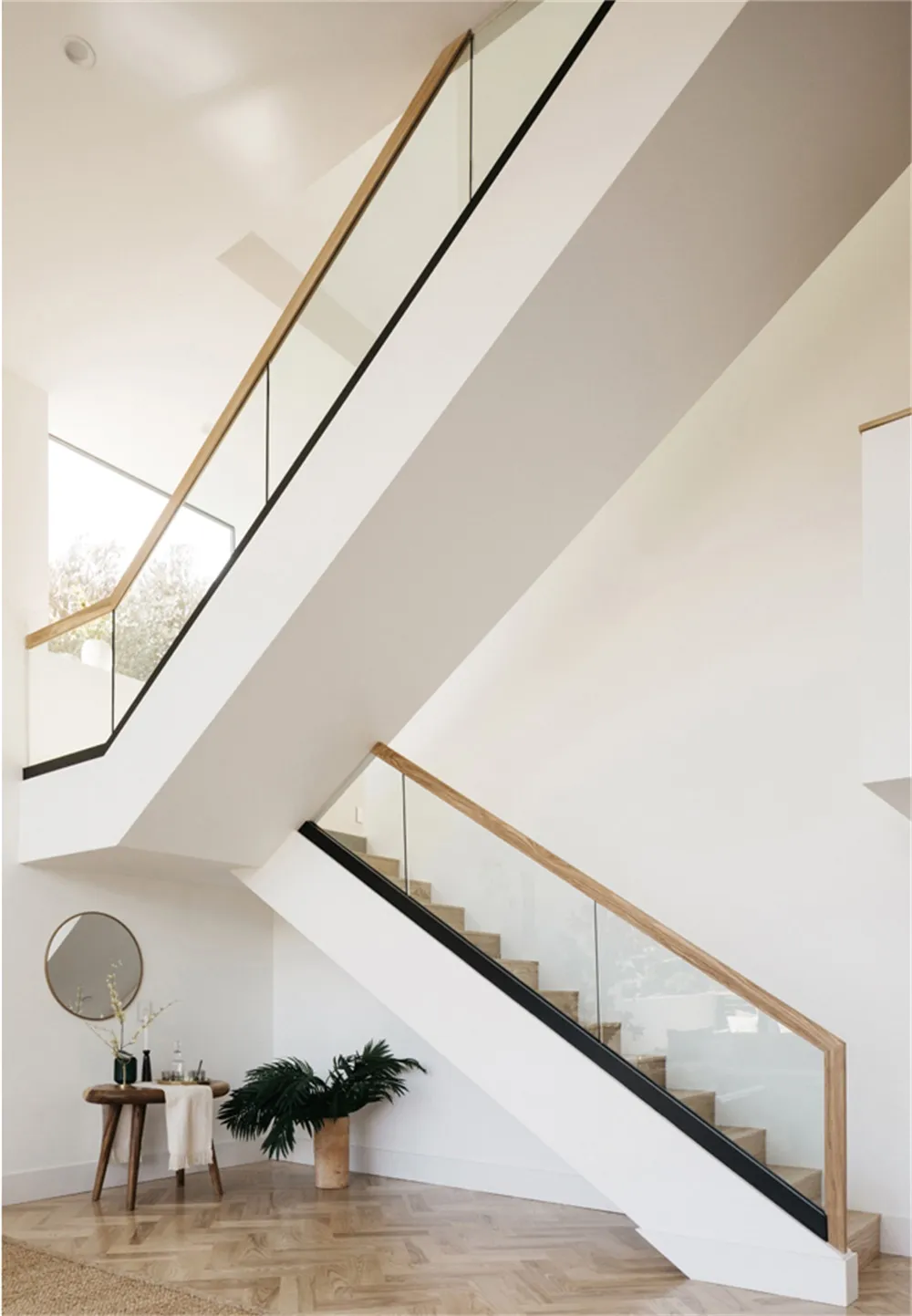 Modern staircase design featuring concrete steps, glass balustrades, and wooden railings.