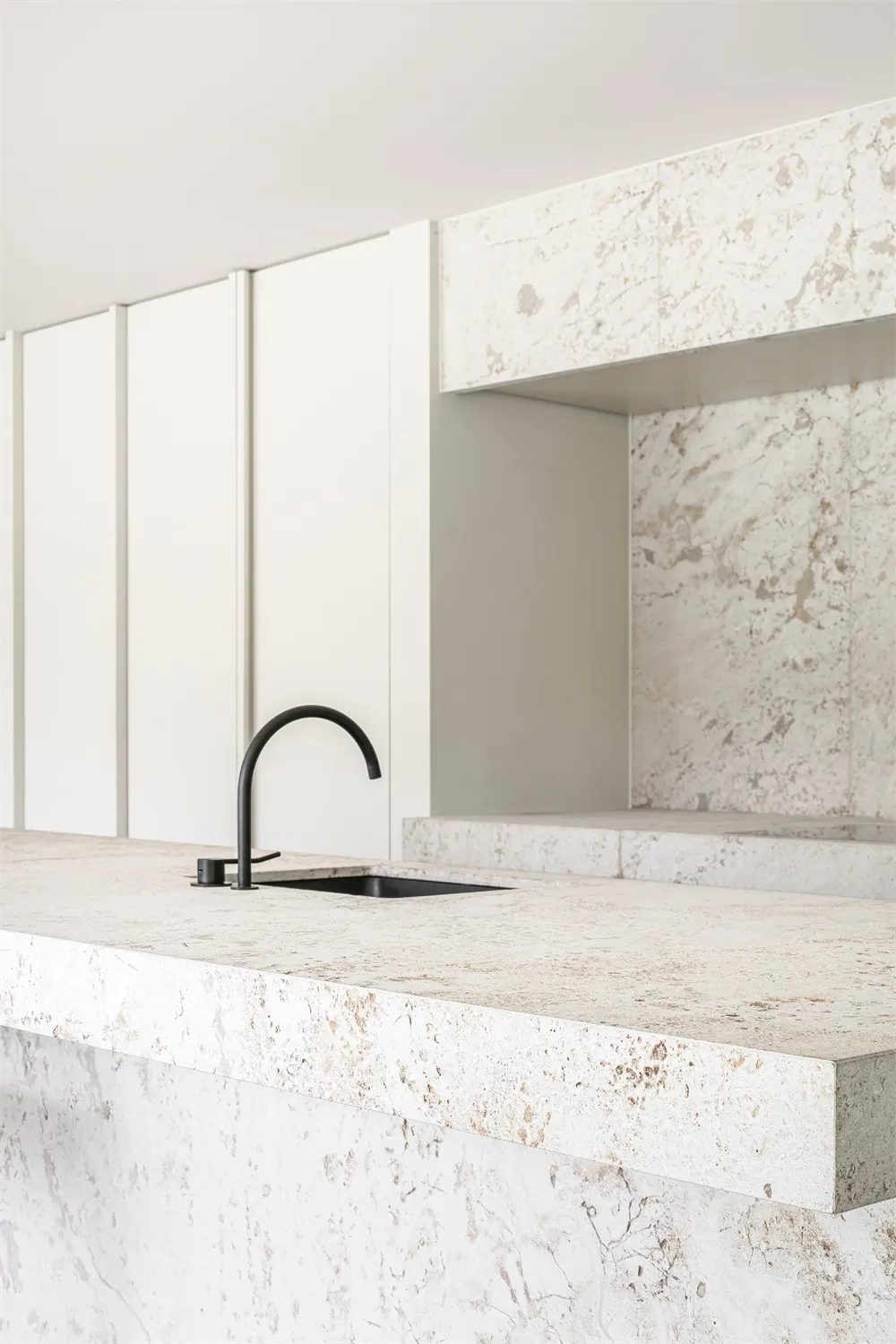 Modern minimalist kitchen featuring white marble countertops and backsplash.
