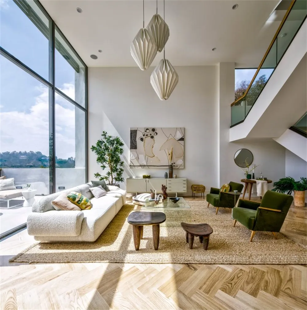 A contemporary living room featuring white and green furniture, a woven rug, and geometric light fixtures.