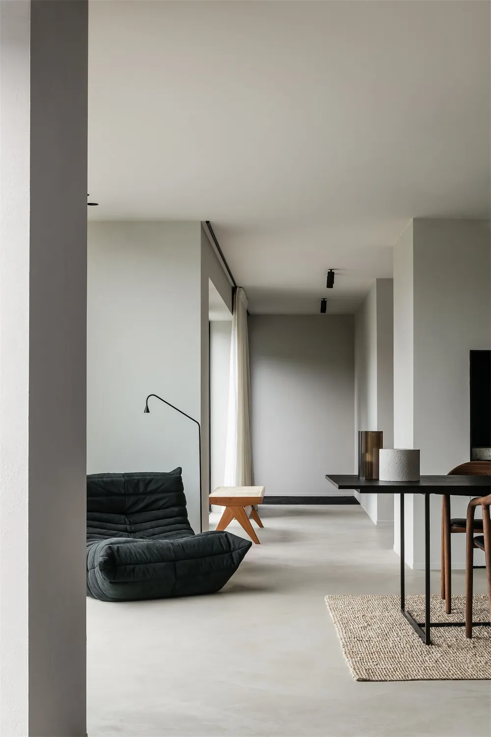 Contemporary living room with minimalist design featuring concrete flooring, minimalist furniture, and ambient lighting.