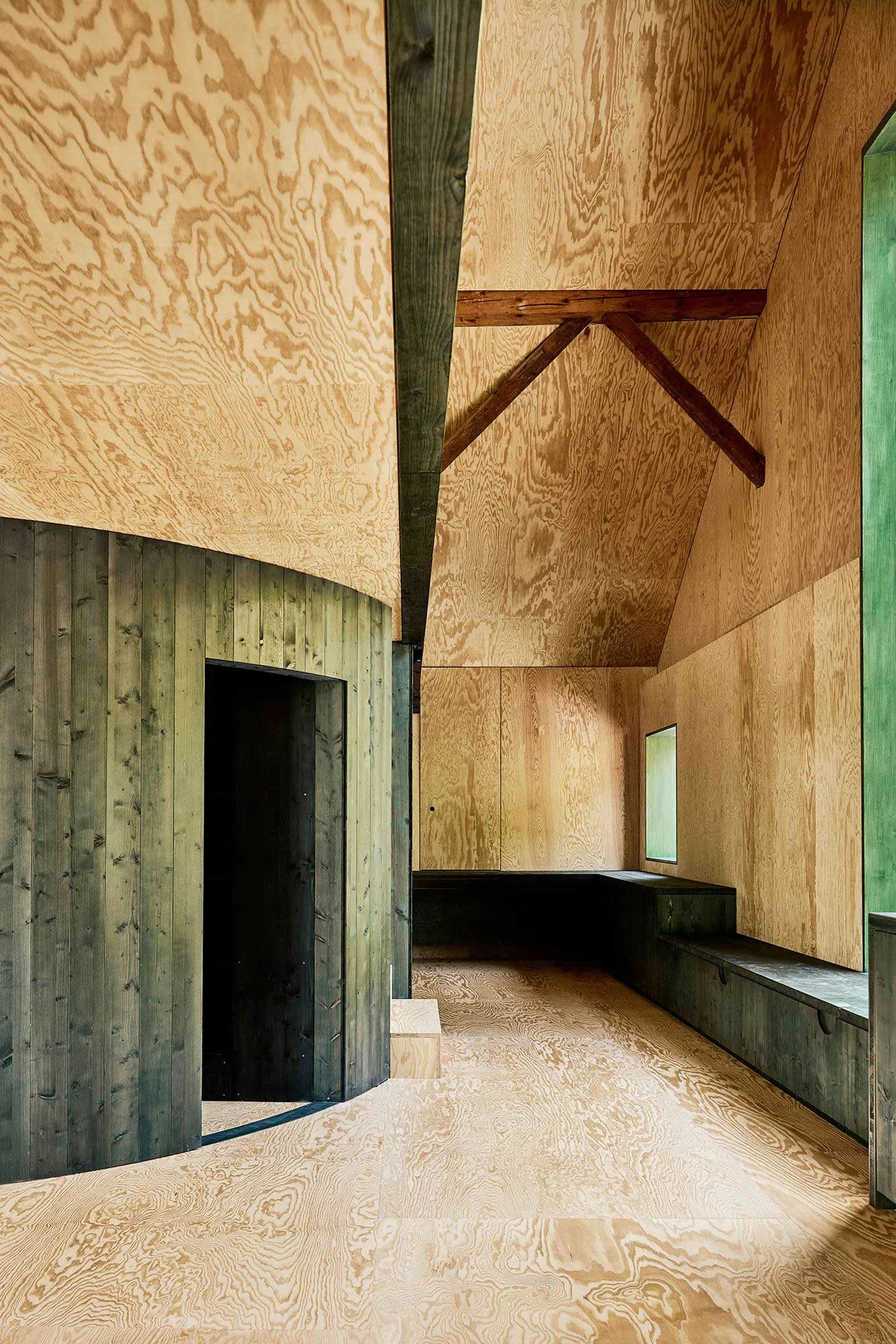 A modern hallway with plywood walls and storage benches.