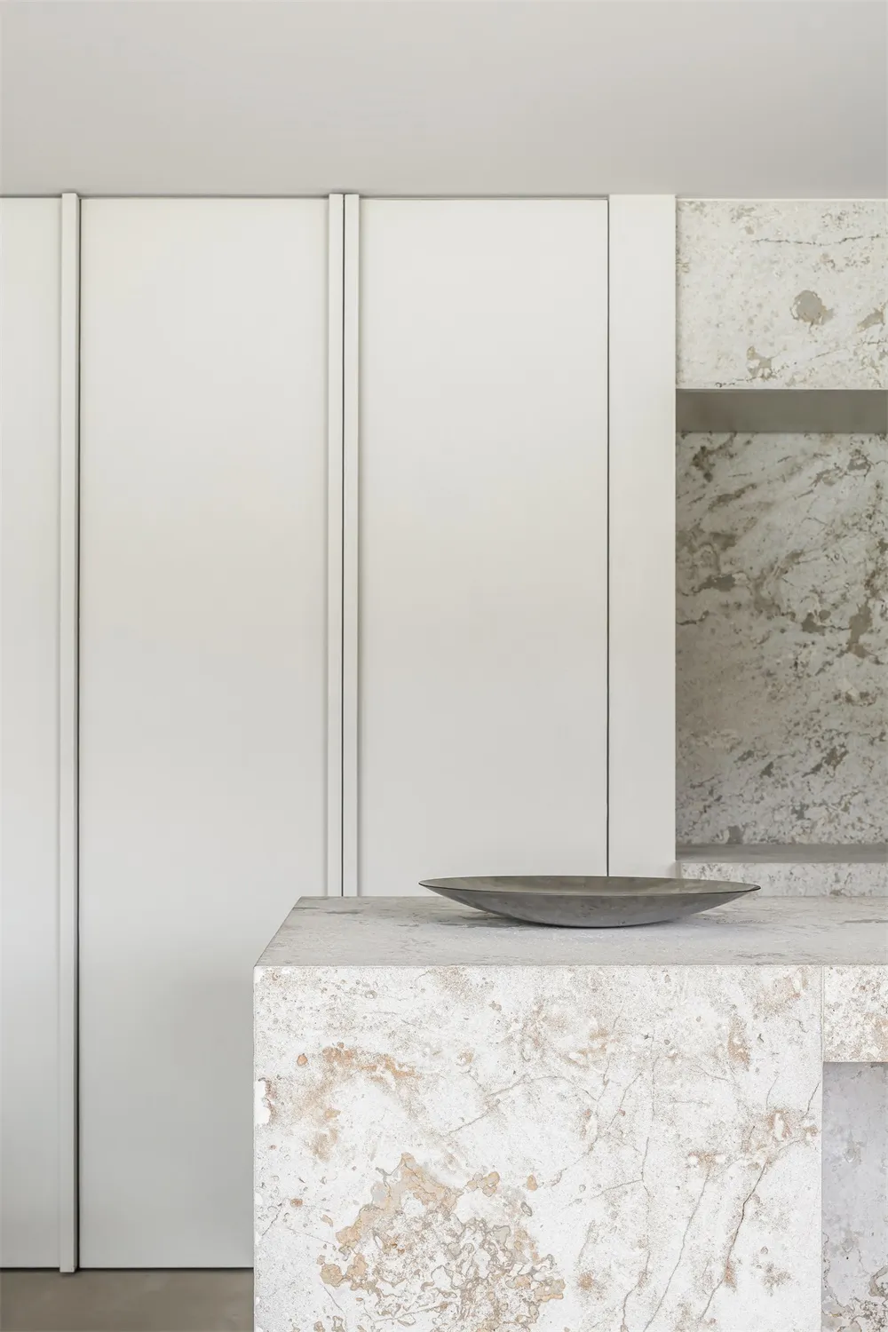 A modern minimalist kitchen with marble countertops and sleek, white cabinetry.