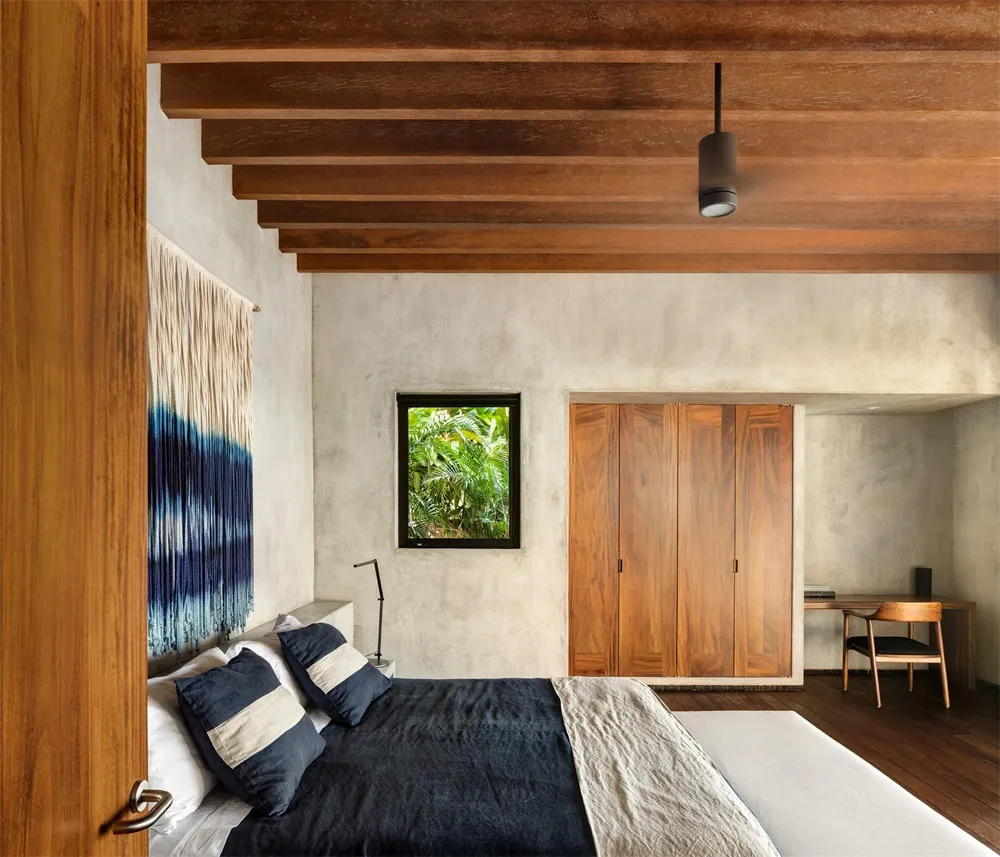 A minimalist bedroom with concrete walls and a wooden bed frame.