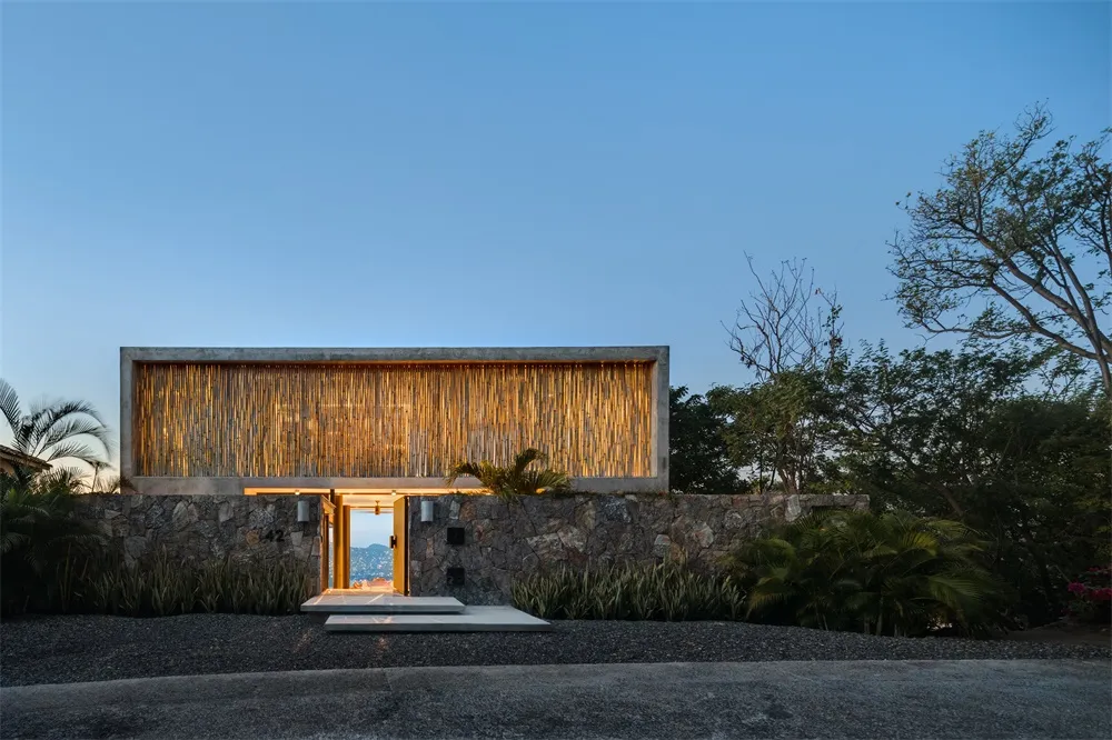 A minimalist residential exterior featuring concrete and natural lighting.