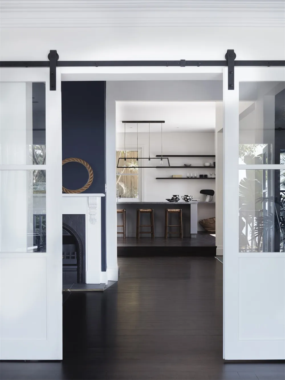 Modern kitchen designed with black and white color scheme, featuring wood-road-hardwood flooring and sleek white cabinetry.
