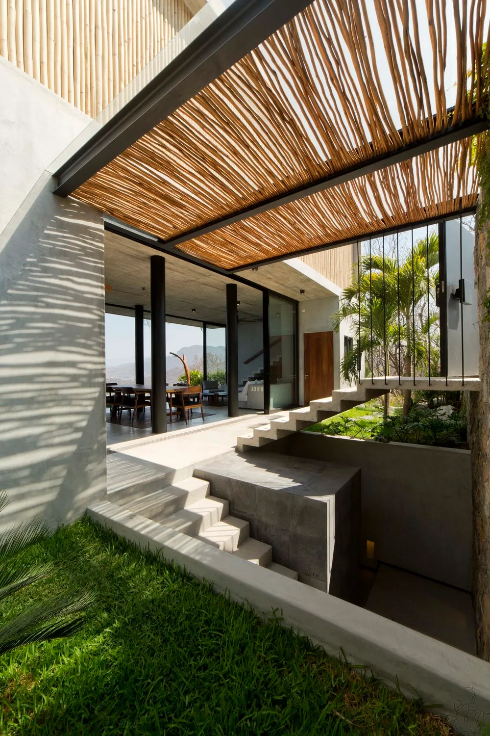 A modern house with a concrete exterior, featuring a layered wooden roof structure.