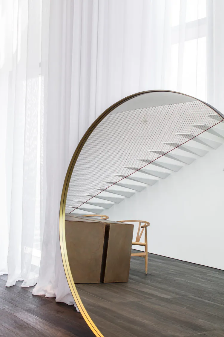 Modern interior design featuring a glass staircase with metal railing and wooden accents.