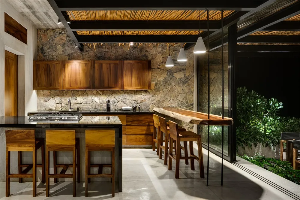 Contemporary residential kitchen with wooden cabinets and countertops, stone backsplash, and seating area.