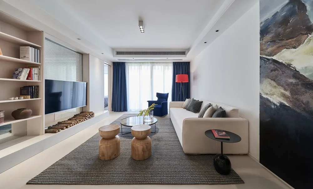 Modern minimalist living room featuring a white sofa with wooden stools, a black side table, and a rug. Blue curtains and a r