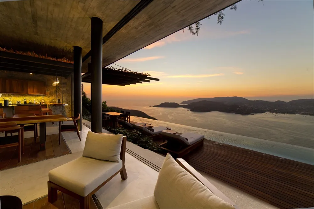 Modern residential patio featuring wood, concrete, and glass elements at sunset.