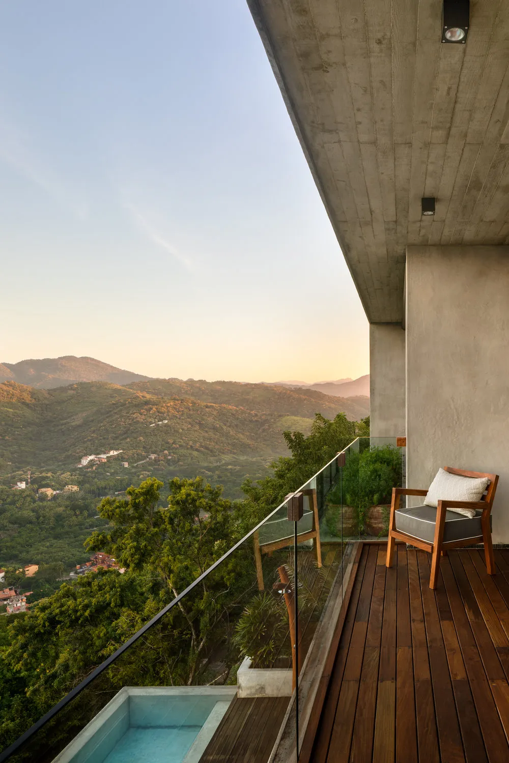 A modern residential balcony featuring concrete, glass, and wooden elements.