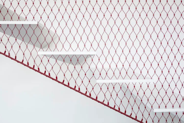 Minimalist design showing concrete stairs with metal netting and red netting on a white background.