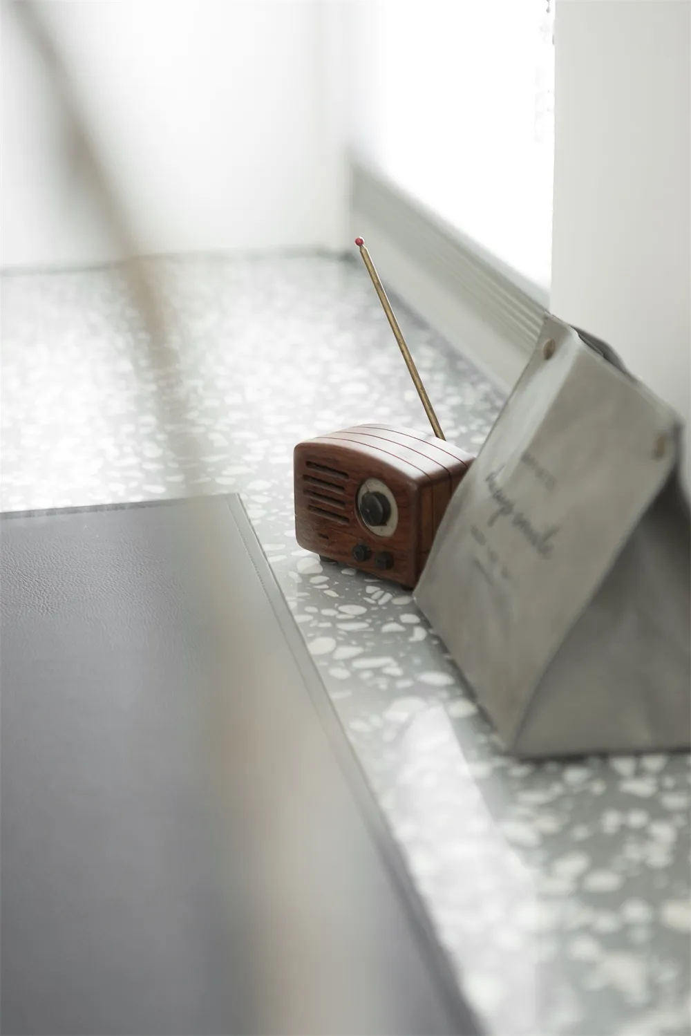 A minimalist living space with a terrazzo-patterned floor and a vintage radio and bag.