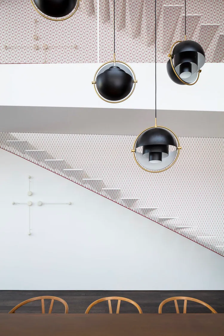 A modern dining room with contemporary lighting fixtures and a geometric staircase.