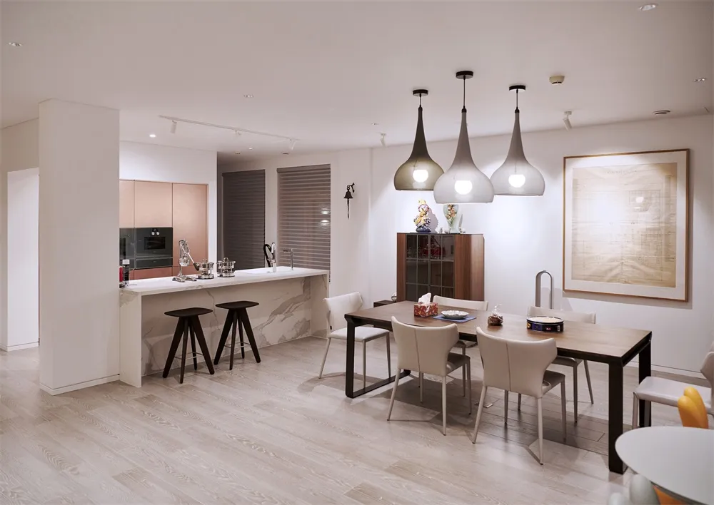 Modern kitchen and dining area with white marble countertops and flooring, pendant lights, and minimalist design.