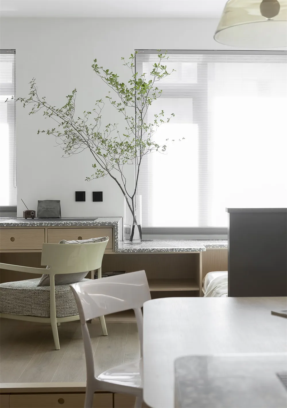 A modern minimalist kitchen featuring a terrazzo countertop and light-colored furniture.