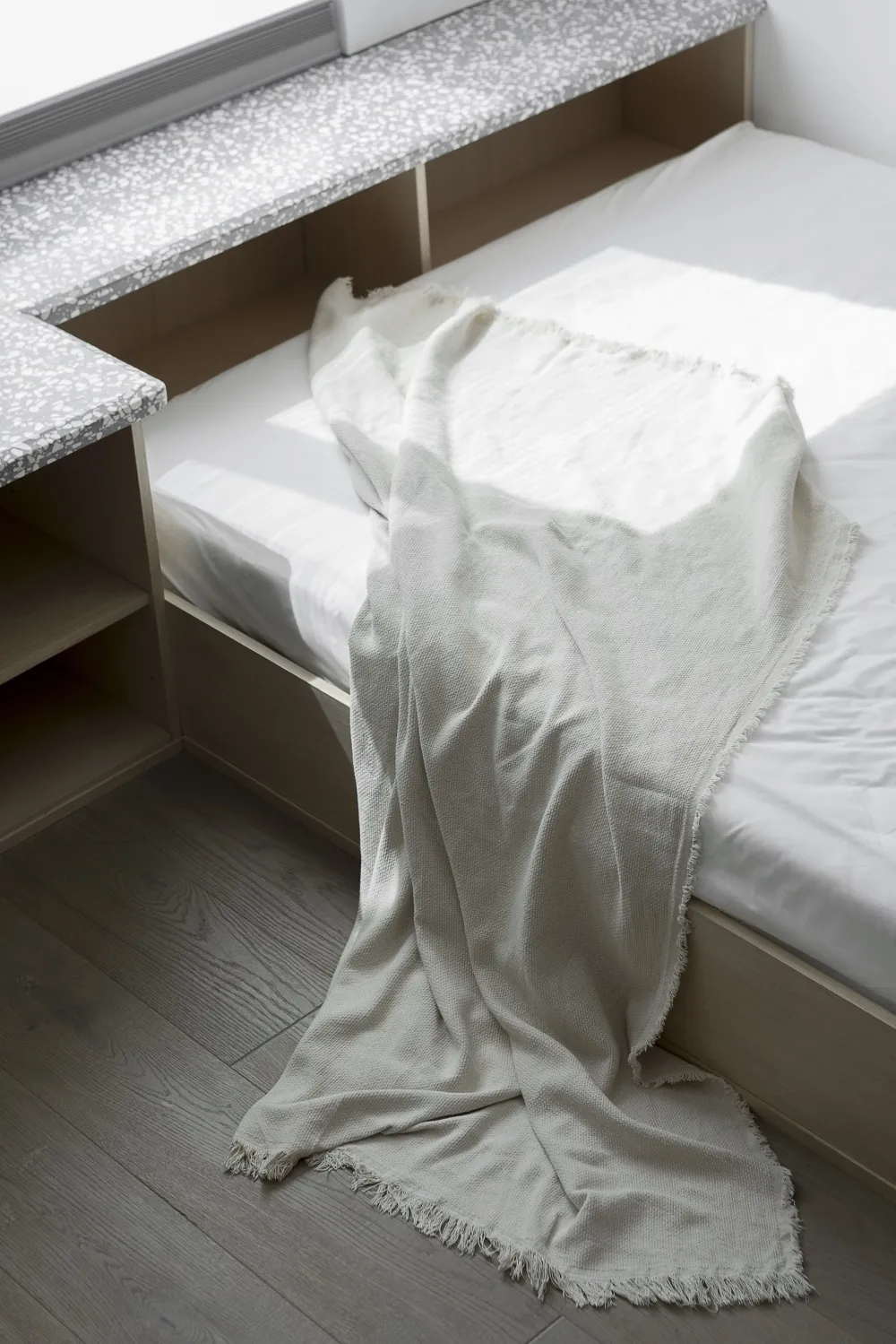 A minimalistic bedroom with a cotton-blend blanket draped over the bed.
