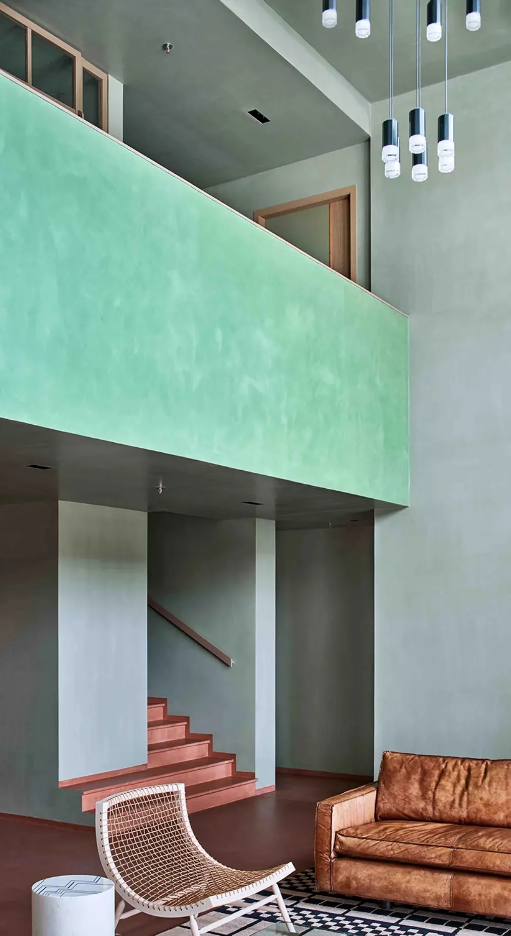 A modern interior space with concrete stairs, a wooden bench, and a metallic hanging light fixture