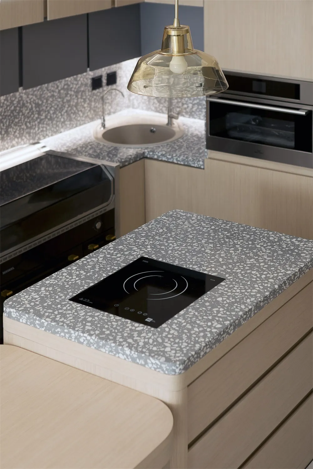 Modern kitchen featuring a terrazzo countertop with an integrated cooktop.
